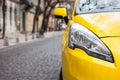 Closeup headlight of modern sport yellow car. Car exterior details over city background.