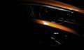 Closeup headlight of shiny orange luxury SUV compact car. Elegant electric car technology and business concept. Hybrid auto