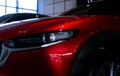 Closeup headlight of shiny red luxury SUV car in showroom. Elegant electric car with sport design. Car parked in showroom. Car Royalty Free Stock Photo