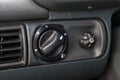Closeup of a headlight tilt adjustment knob on a black old plastic panel of a Russian car with white signs