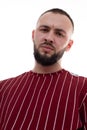 Closeup headshot vertical image of unshaven frowned man face looking at camera in red uniform. Hipster low angle view