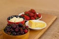 Closeup of healthy breakfast: cottage cheese, strawberries, cherry and sliced cheese on wooden board. Retro styled photo.