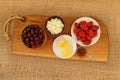 Closeup of healthy breakfast: cottage cheese, strawberries, cherry and sliced cheese on wooden board. Retro styled photo.