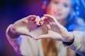 Closeup heart hands of streamer woman cyber gamer online video games showing to subscribers, blue neon color
