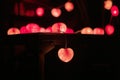 Closeup heart shape of led lights line puts on the wooden table decorated in the darkroom