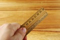 Closeup high angle shot of a person holding an old wooden ruler over a wooden surface Royalty Free Stock Photo