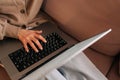 Closeup high-angle view of unrecognizable middle-aged woman using laptop, typing on keyboard, writing email or message Royalty Free Stock Photo