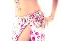 Closeup hips of bellydancer wearing white and pink colored skirt, posing performing dance moves, bright studio
