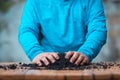 Closeup of a Hispanic boy in a blue sweater preparing the soil on the table for planting