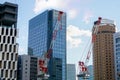 Hoisting cranes working on city landscape view and glass office building with blue sky Royalty Free Stock Photo