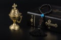 Closeup of Holy Bible, rosary beads with cross and incense burner on black background. Religion concept and faith Royalty Free Stock Photo