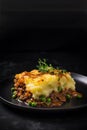 Closeup of homemade cottage Shepherd's traditional pie with greens on black with copy space