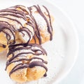Closeup of homemade profiteroles with whipped cream and chocolate filling, square