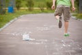 Closeup of hopscotch drawn with chalk on asphalt road and jumping boy. Children games and outdoor activities Royalty Free Stock Photo