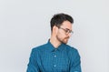 Closeup horizontal portrait of handsome male model in glasses and blue shirt, looking down posing against white studio wall Royalty Free Stock Photo