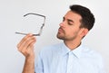 Closeup horizontal portrait of unshaven handsome serious male touches rim of spectacles decide to wear, posing against white Royalty Free Stock Photo