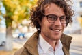 Closeup horizontal portrait of young happy business man with glasses smiling and posing outdoors. Male student in autumn street. Royalty Free Stock Photo