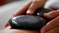 Closeup of a hot stone being used to apply gentle pressure on a persons muscles promoting deep tissue relaxation.