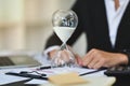 Closeup hourglass on office table with blurred businessman working on background Royalty Free Stock Photo