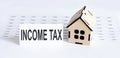 Closeup of house wooden model with blank for text INCOME TAX on the chart background Royalty Free Stock Photo