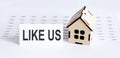 Closeup of house wooden model with blank for text LIKE US on chart background Royalty Free Stock Photo