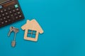 Closeup of house wooden model and keys with calculator on blue background. Mortgage property insurance buy dream home shopping Royalty Free Stock Photo