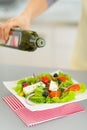 Closeup on housewife adding olive oil in salad