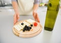 Closeup on housewife giving olives and cheese on cutting board