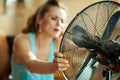 Closeup on housewife using fan suffering from summer heat