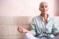 Closeup of HSenior Woman Posing in Yoga Asana Pose on Couch indoors. Sitting with Folded Legs