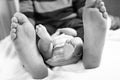 Closeup of huge feet of father and little newborn baby