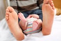 Closeup of huge feet of father and little newborn baby