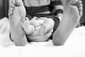 Closeup of huge feet of father and little newborn baby. Big feet of adult and tiny legs of child. Happy parenthood Royalty Free Stock Photo