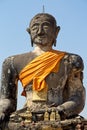 Closeup of huge stone statute of buddha wrapped in orange clock monastry Phonsavan, Laos