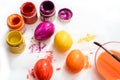 Closeup human hand painting easter egg with paintbrush. Yellow, orange, red and purple egg.Painting eggs for Easter.