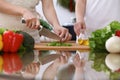 Closeup of human hands cooking in kitchen. Mother and daughter or two female cutting green salad or herbs. Healthy meal