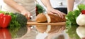 Closeup of human hands cooking in kitchen. Mother and daughter or two female friends cutting bread for dinner Royalty Free Stock Photo