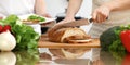 Closeup of human hands cooking in kitchen. Mother and daughter or two female friends cutting bread for dinner Royalty Free Stock Photo