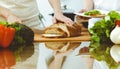 Closeup of human hands cooking in kitchen. Mother and daughter or two female friends cutting bread for dinner Royalty Free Stock Photo