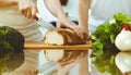 Closeup of human hands cooking in kitchen. Mother and daughter or two female friends cutting bread for dinner Royalty Free Stock Photo