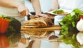 Closeup of human hands cooking in kitchen. Mother and daughter or two female friends cutting bread for dinner Royalty Free Stock Photo