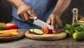 Closeup on human hands cutting vegetables on wooden cutting board with knife