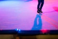 Closeup of human legs in old skates on outdoor public ice rink. Young figure skating on frozen lake in snowy winter park at night Royalty Free Stock Photo