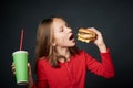 Closeup of hungry little girl going to bite a hamburger