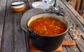 Closeup of a hunting soup of tomatoes and red pepper in a large pan on a wooden table