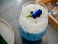Closeup iced butterfly pea milk tea topping with flower