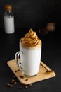 Closeup of Iced Dalgona coffee in glass mug on dark background. Trendy refreshment creamy whipped coffee.