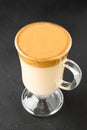 Closeup of Iced Dalgona coffee in glass mug on dark background. Trendy refreshment creamy whipped coffee. Korean coffee