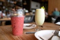 Closeup iced strawberry smoothie in transparent take away cup on wooden table