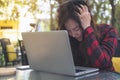 An Asian business woman with feeling stressed and tired , close her eyes while using laptop on glass table sitting at outdoor Royalty Free Stock Photo